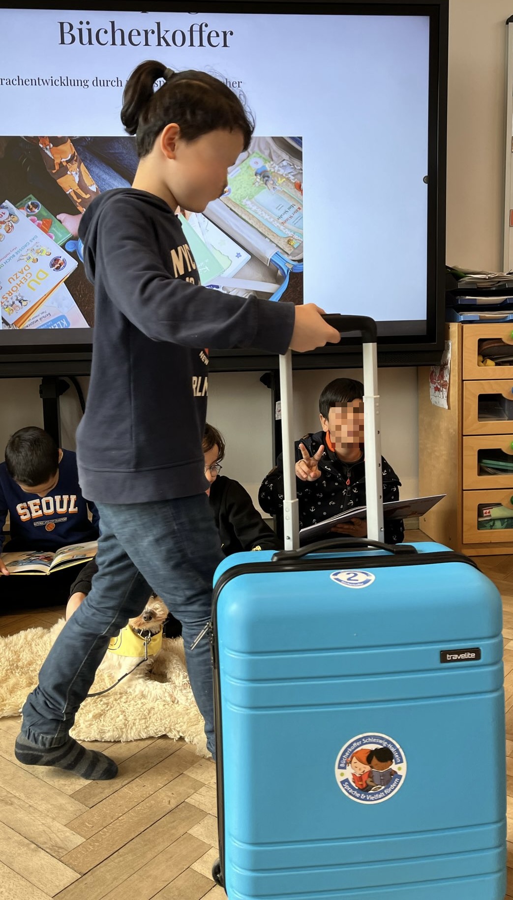 Schüler schiebt Bücherkoffer ins Klassenzimmer